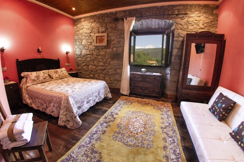 Habitación roja con pared de piedra y vistas exteriores